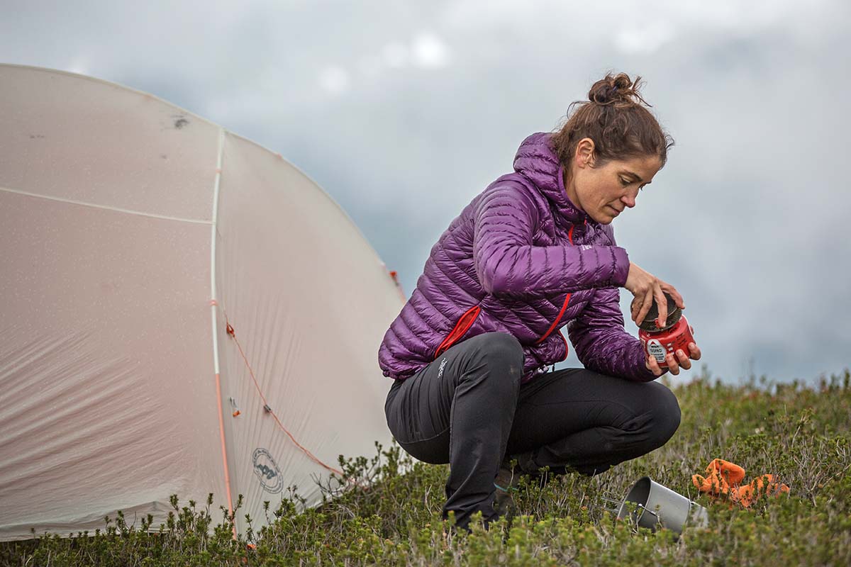 Setting up stove in Mountain Hardwear Ghost Whisperer 2 down jacket with tent in background